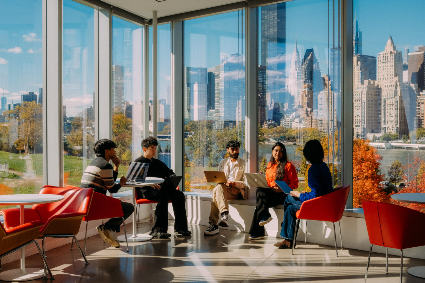 Students sitting on the Cornell Tech campus with a Manhattan skyline in the background